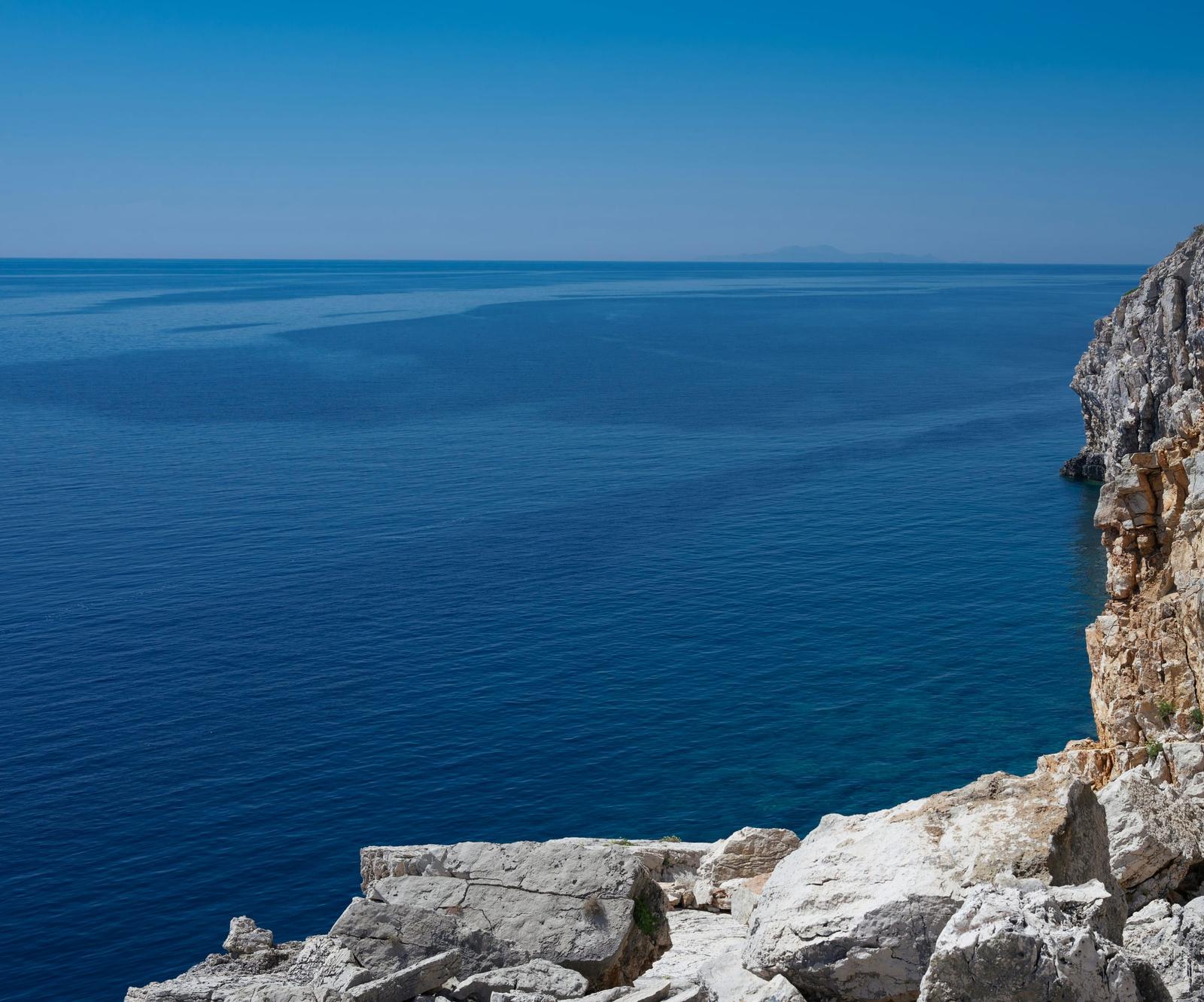 Falaise calcaire au-dessus d'une mer bleu profond, sous un ciel dégagé